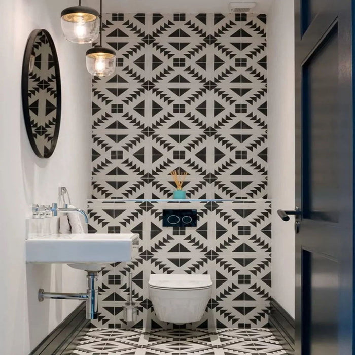 Almeira Azteca Feinsteinzeug-Bodenfliesen im marokkanischen Stil in einem modernen Badezimmer, mit einem markanten geometrischen Dreiecksmuster in Schwarz und Weiß, kombiniert mit weißen Metro-Wandfliesen, Format 20 × 20 cm.