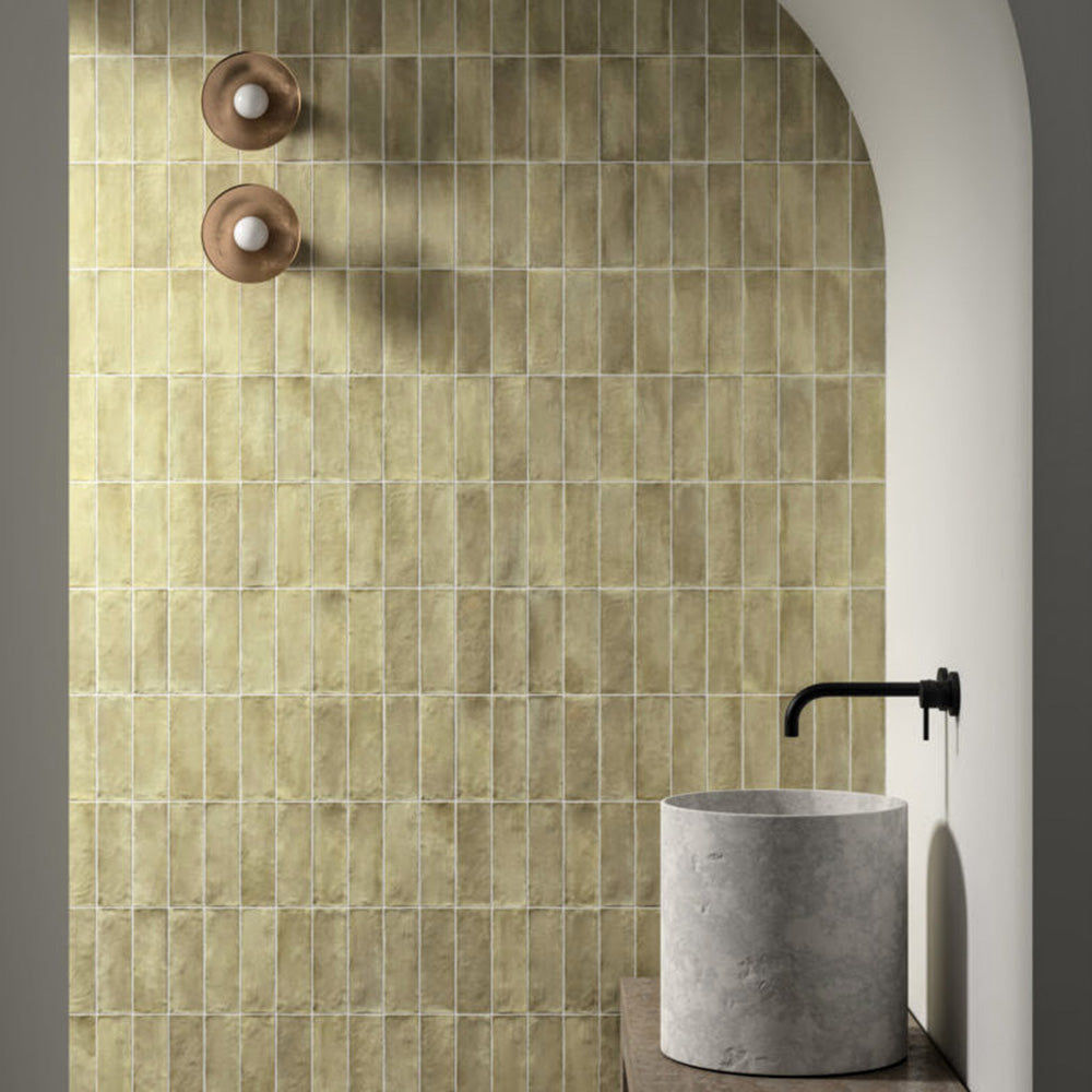 Badezimmer mit Zellige Waldgrün Matt Keramik-Riemchenfliesen im marokkanischen Stil im Format 6,5 × 20 cm, im Duschbereich mit Rundbogen verlegt. Die sanfte grüne Farbvariation und die handgefertigte Optik werden durch ein minimalistisches Betonwaschbecken und mattschwarze Armaturen ergänzt.