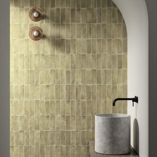 Badezimmer mit Zellige Waldgrün Matt Keramik-Riemchenfliesen im marokkanischen Stil im Format 6,5 × 20 cm, im Duschbereich mit Rundbogen verlegt. Die sanfte grüne Farbvariation und die handgefertigte Optik werden durch ein minimalistisches Betonwaschbecken und mattschwarze Armaturen ergänzt.