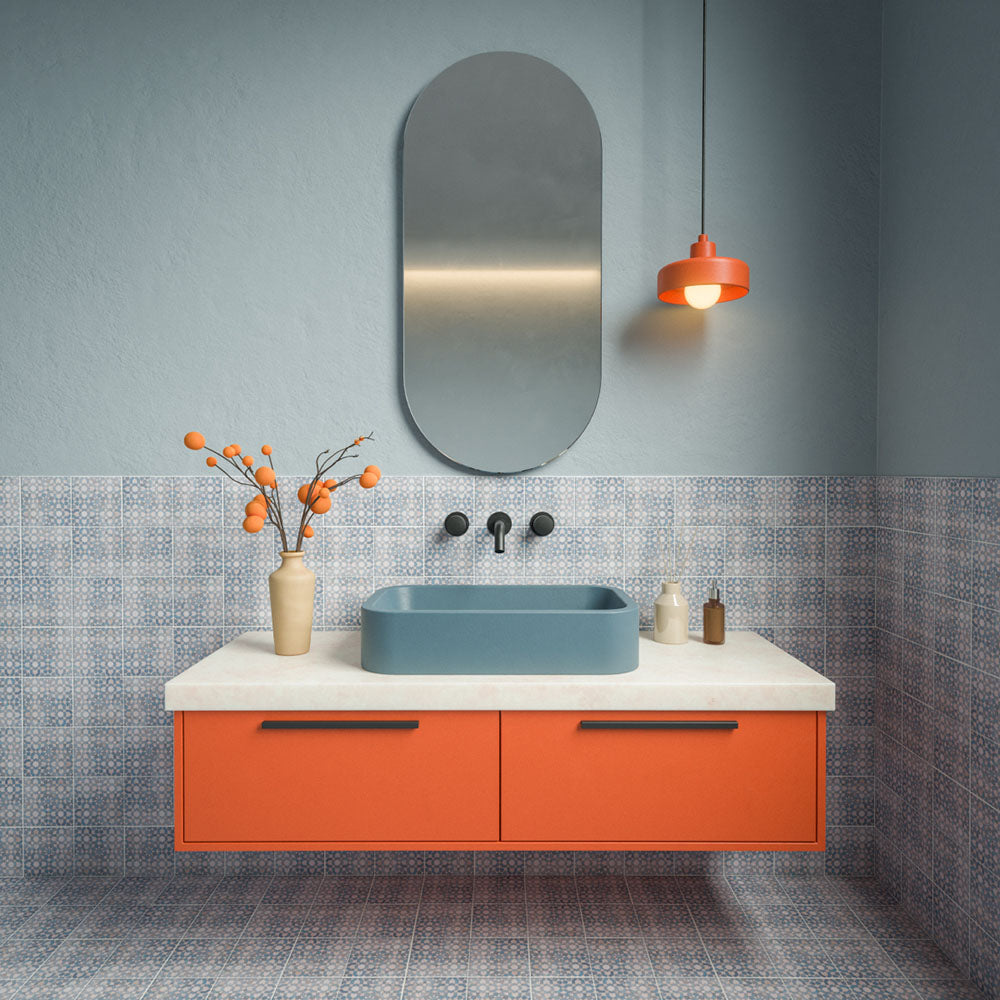 Badezimmer mit Berber Tetuan Blau Musterfliesen im Format 15 × 15 cm im marokkanischen Stil an Wänden und Boden, mit einem detailreichen blau-weißen Design, kombiniert mit einem blauen Waschbecken, einem orangefarbenen Waschtischunterschrank und einer passenden auffälligen Beleuchtung.
