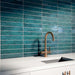Küchenrückwand mit Bora Bora Brick Amun Blue Wandfliesen im Format 6,5 × 32,8 cm, die die satten blau schimmernden Flux-Glasureffekte zur Geltung bringen. Kombiniert mit einer weißen Arbeitsplatte, einem integrierten Spülbecken und einer Armatur in gebürsteter Messingoptik entsteht ein eleganter und zeitgemäßer Look.