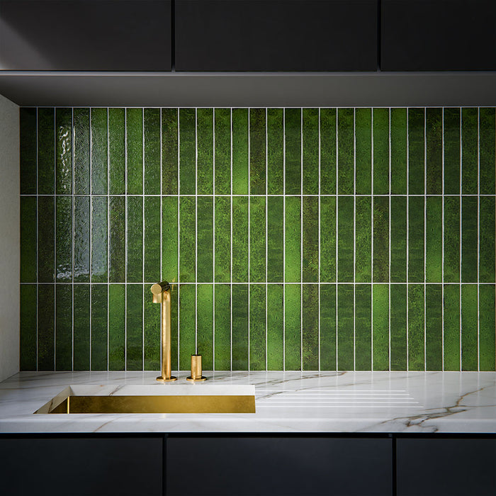 Moderne Küchenrückwand mit Bora Bora Brick Tourmaline Green Wandfliesen im Format 6,5 × 32,8 cm, kombiniert mit dunklen Küchenfronten, einer Arbeitsplatte in Marmoroptik und Armaturen in gebürsteter Messingoptik für eine luxuriöse Ausstrahlung.