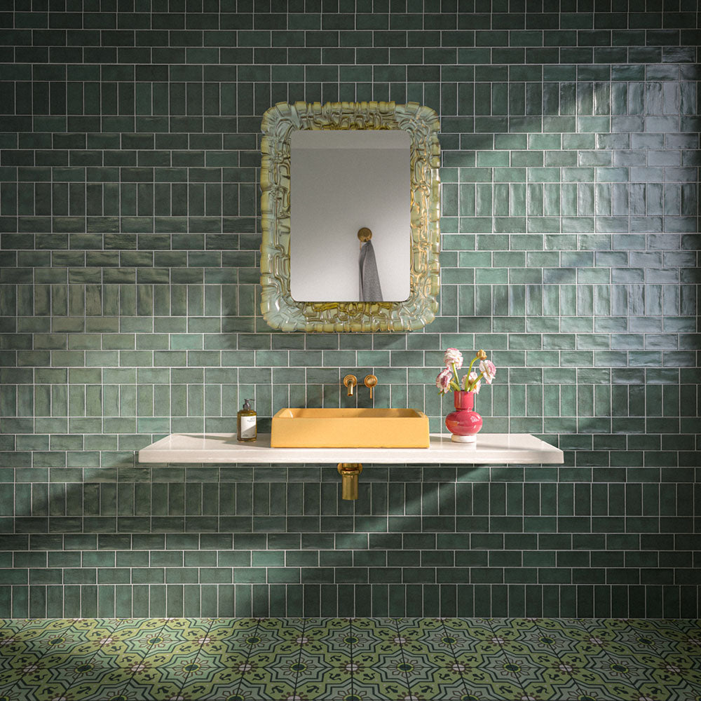 Badezimmer mit Dordogne Grüne Kiefern Rustikale glänzende Wandfliesen im Format 7,5 × 15 cm in satten Grüntönen mit handwerklich inspirierter Farbvariation. Kombiniert mit einem schwebenden Waschtischunterschrank in Weiß, einem senfgelben Waschbecken, Armaturen in Messingoptik, einem verzierten Spiegel und gemusterten grünen Bodenfliesen entsteht ein ausdrucksstarkes und stilvolles Badezimmerdesign.