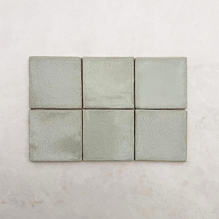 Dordogne Matcha Green Rustic Gloss Wandfliesen im Format 10 × 10 cm in sanften Grüntönen mit dezenten Farbvariationen und rustikaler Glanzoberfläche, die den handwerklich inspirierten Charakter und die leicht strukturierte Oberfläche der Kollektion hervorheben.