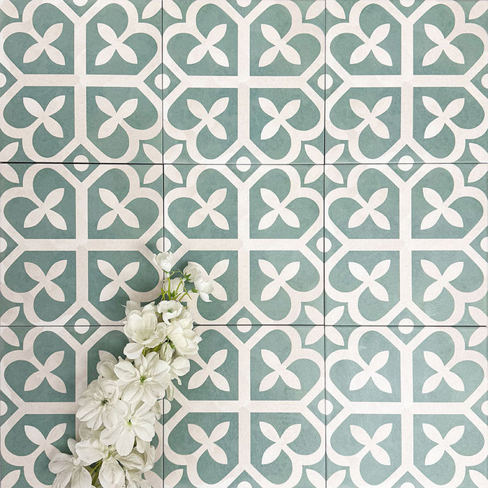 Kuba Ivy Grün Feinsteinzeugfliesen im viktorianisch-marokkanischen Stil im Format 20 × 20 cm, gezeigt in einer Flatlay-Darstellung mit dekorativen Pflanzen, um das geometrische Design hervorzuheben.