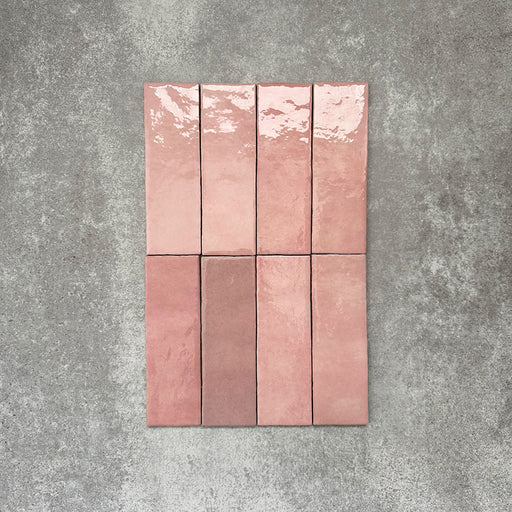 Flatlay von Zellige Rosa Brick Keramikfliesen im marokkanischen Stil im Format 6,5 × 20 cm, gezeigt in sanften Blush-, Altrosa- und Terrakotta-Pinktönen mit feiner tonaler Variation und leicht unregelmäßigen Kanten. Vertikal im Ziegelverband auf strukturiertem grauem Hintergrund arrangiert, um die handwerkliche Zellige-Glasur hervorzuheben.