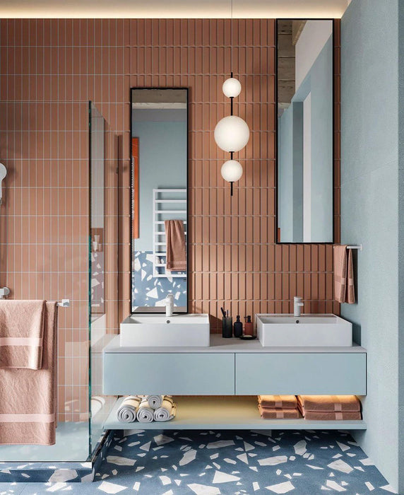Badezimmer mit Melodie Rock Terrazzo Blau 60 × 60 cm Feinsteinzeug-Bodenfliesen mit sanft blauer Basis und großen weißen Zuschlägen, kombiniert mit vertikal verlegten Terrakotta-Wandfliesen, schwebendem Waschtisch und einem klaren, designorientierten Look.