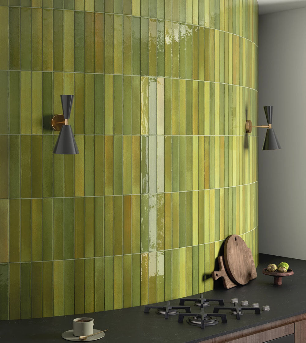 Nahaufnahme der Lisbon Olive Green Wandfliesen aus Feinsteinzeug im handwerklichen Stil im Format 5 × 30 cm, vertikal auf einer geschwungenen Küchen-Akzentwand verlegt. Die Aufnahme zeigt die satten Olivgrüntöne, feine Farbvariationen und die glänzende, handwerklich inspirierte Oberfläche der Kollektion.