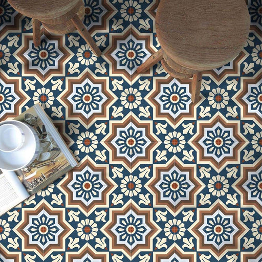 Wohnbereich mit Berlin Großartig Feinsteinzeugfliesen im Format 20 × 20 cm im marokkanisch inspirierten Stil. Gezeigt wird ein detailreiches geometrisches Muster in Blau-, Braun- und Cremetönen, kombiniert mit rustikalen Holzhockern und warmen Naturmaterialien für eine ausdrucksstarke, charaktervolle Wirkung.