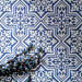 Draufsicht auf Berlin Trondite Feinsteinzeugfliesen im Format 20 × 20 cm im viktorianisch-marokkanisch inspirierten Stil, verlegt in einem sich wiederholenden Muster in Blau und Weiß. Ergänzt mit dekorativem Blattwerk, um das detailreiche, traditionell inspirierte Design hervorzuheben.