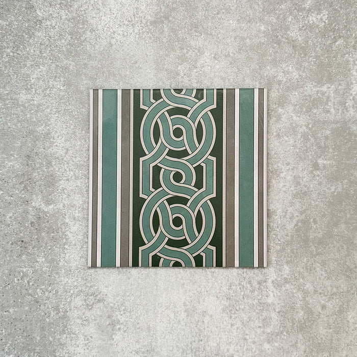 Berlin Mitte Seitenfliese / Bordüre im Format 20 × 20 cm im viktorianisch-marokkanisch inspirierten Stil aus Feinsteinzeug. Mit ineinandergreifendem, geometrischem Bordürendesign in Salbeigrün, Dunkelgrün und sanften Grautönen, entwickelt zur Einfassung von Berlin Mitte Musterfliesen in klassischen, viktorianisch inspirierten Bodenverlegungen.