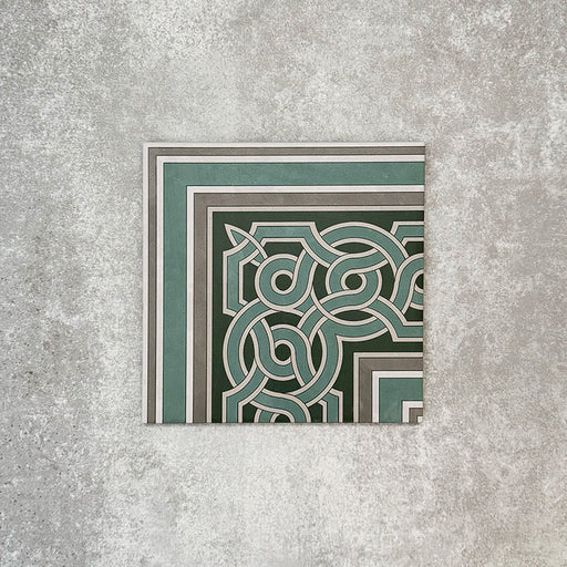 Einzelne Berlin Mitte Bordürenecke im Format 20 × 20 cm im viktorianisch-marokkanisch inspirierten Stil aus Feinsteinzeug, dargestellt in einer Produktszene. Gezeigt wird ein dekoratives Eckdesign in Grün-, Salbei- und Cremetönen, inspiriert von traditionellen Fliesenlayouts in viktorianischen Eingangsbereichen.